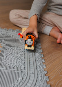 Çocuğun yanında Puzzle Tren Yolu ortopedik duyu matı